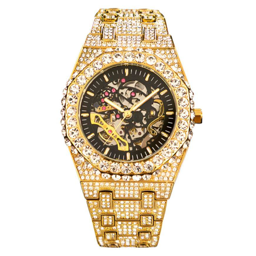 A fully iced-out mechanical watch with a gold band and dial, surrounded by high-quality stones.