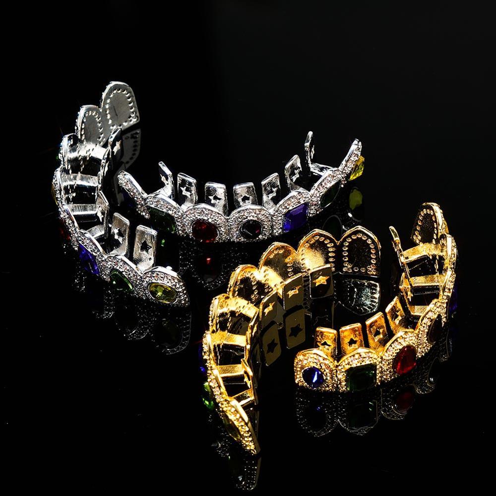 DatNewDrip gold and silver colored gem grillz with multicolor gemstones on reflective black background