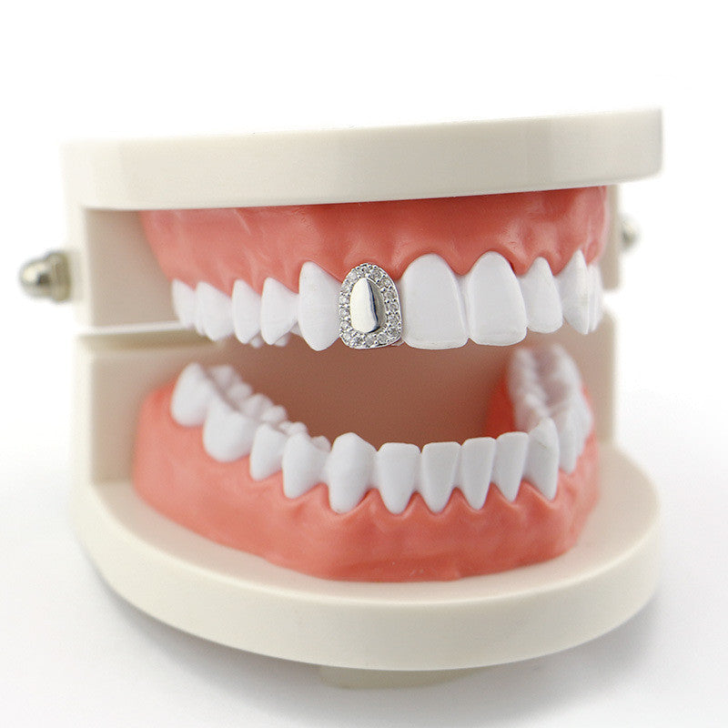 Dental model with white teeth showcasing iced out single tooth grillz on upper front tooth