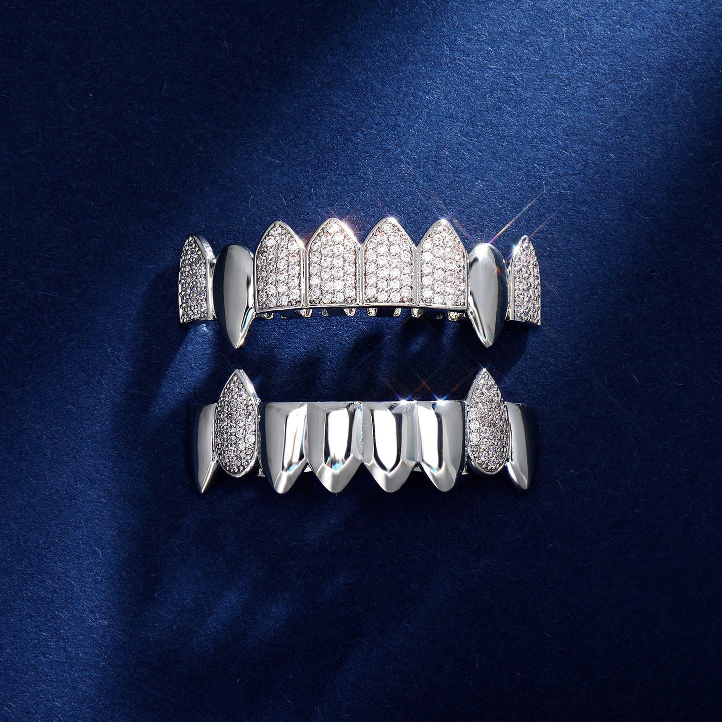 Silver iced out fang grillz set with pave crystals top and bottom fangs displayed on dark blue backdrop