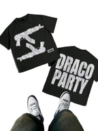 Two black t-shirts with white graphics and text on a concrete floor.