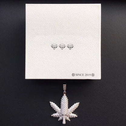 DatNewDrip iced out pot leaf pendant with pave cubic zirconia stones displayed beneath white box