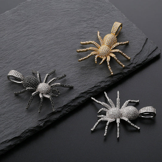 DatNewDrip iced out black spider pendant alongside gold and silver iced spider pendants on slate background