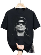 Black t-shirt with a graphic of a person wearing sunglasses and a cap, held by a hand in a clothing store.