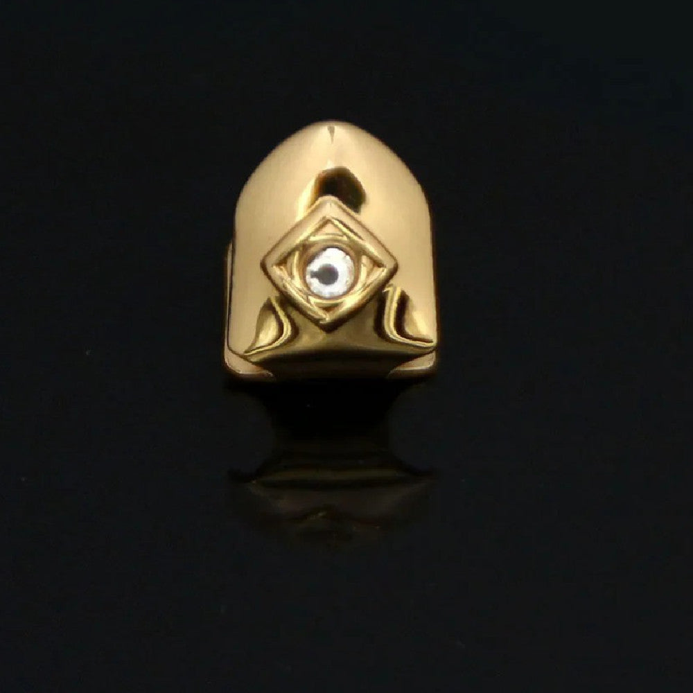 Gold single diamond tooth grillz cap with bezel set diamond and geometric detailing on black background