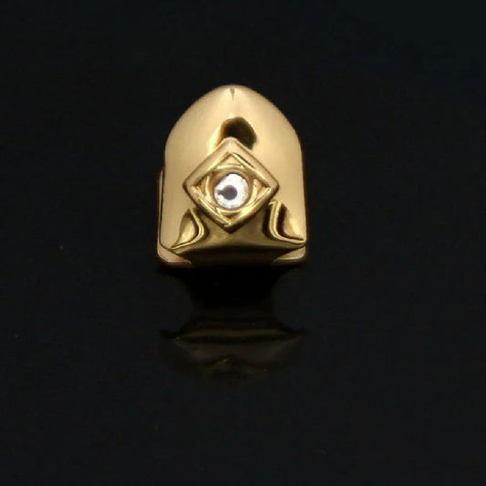 Gold single diamond tooth grillz cap with bezel set diamond and geometric detailing on black background