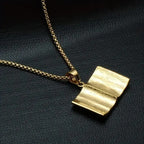 Gold iced out bible pendant on a chain with a textured open book design