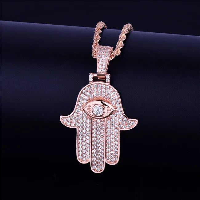 Iced out hamsa hand pendant necklace in rose gold with intricate eye design and sparkling embellishments