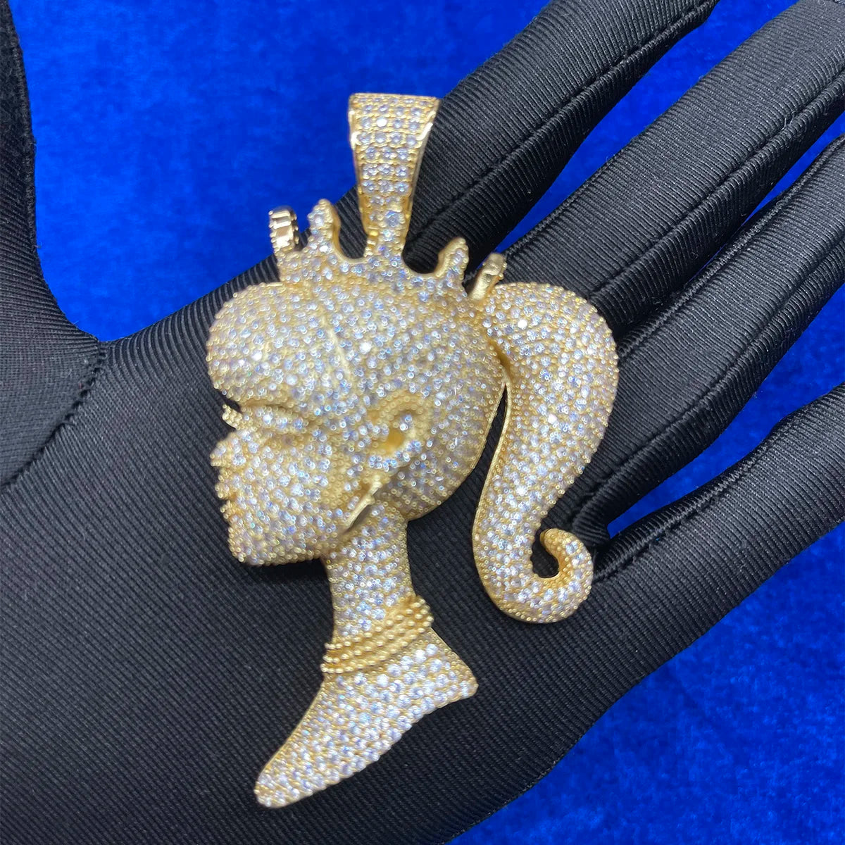 Iced Out queen doll rapper pendant jewelry in gold with sparkling details showcased on a black background